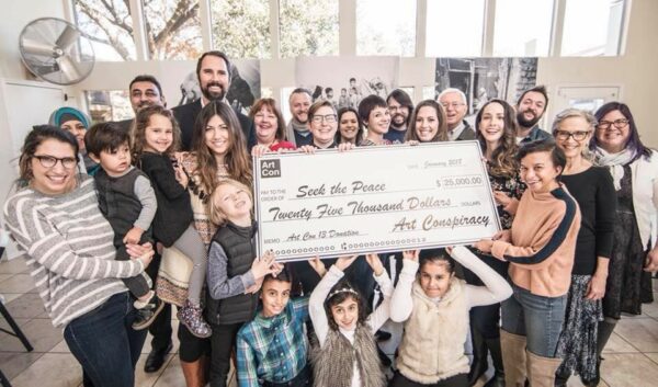 A photograph of a group of people holding a large check for $25,000.