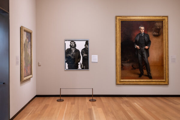 An installation image of a portrait by Richard Avedon hanging in a gallery with 19th century paintings.