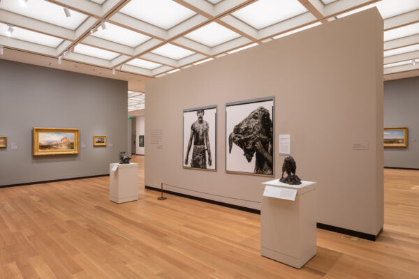 An installation image of portraits by Richard Avedon hanging in a gallery with 19th century paintings.