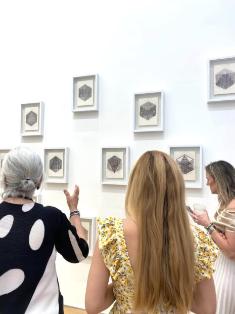 Photo of visitors looking at two dimensional works on a wall