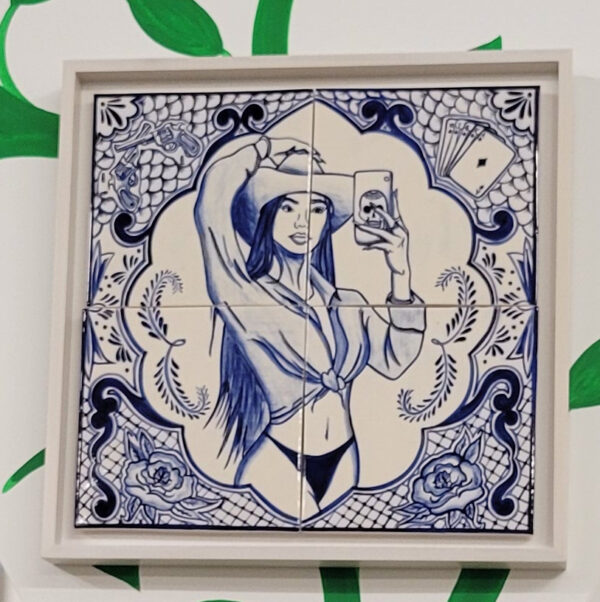 Installation view of blue talavera tiles with the image of a woman taking a selfie