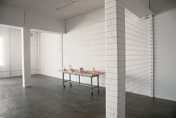 An installation image of a work by Mona Hatoum featuring a table filled with electrified household objects.