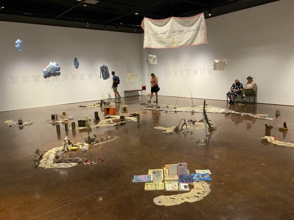 Installation view of objects on the floor and hanging from the ceiling