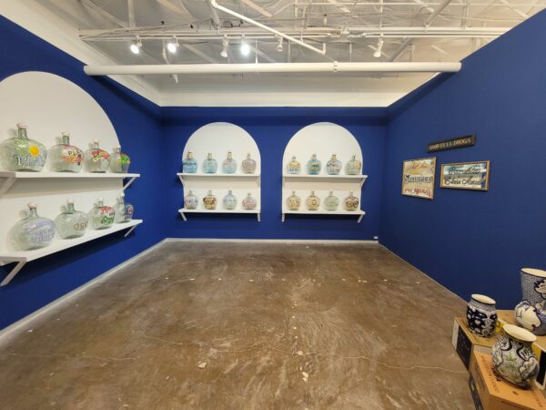 Installation view of hand painted mezcal bottles on shelves