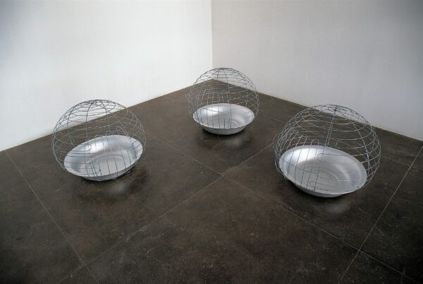 An installation image of three spherical metal wire sculptures by Mona Hatoum.