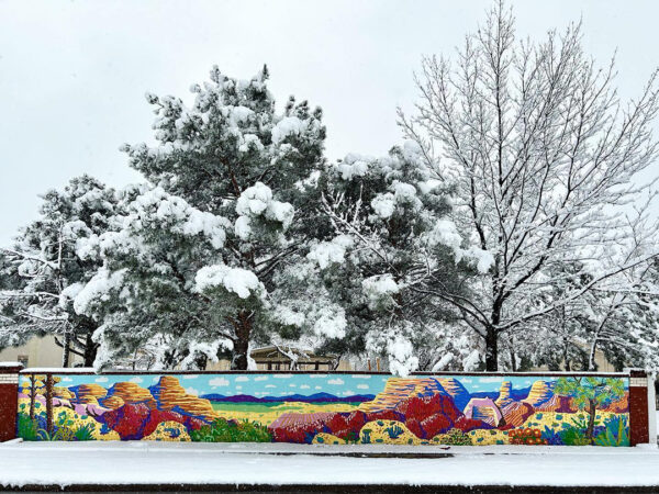 A photograph of a large colorful mural of west Texas painted on an exterior garden wall.