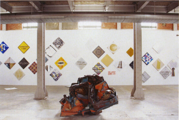 Installation view of artist signs and a crushed ball of metal
