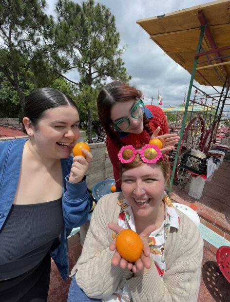 Three women posing with oranges