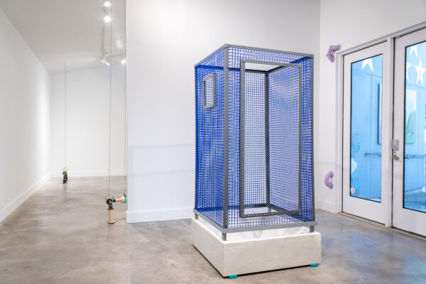 Installation view of a large blue mesh cube on a pedestal