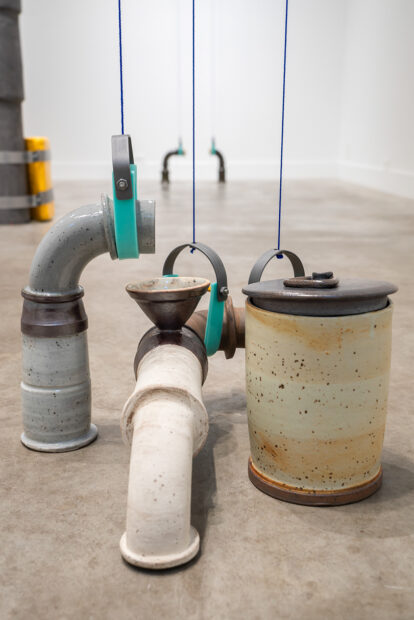 Installation view of pipes and valves in a gallery space