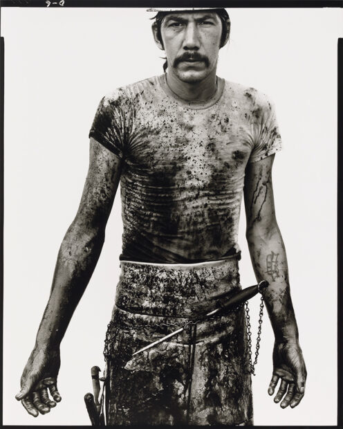 A black and white photograph of a slaughterhouse worker covered in blood.