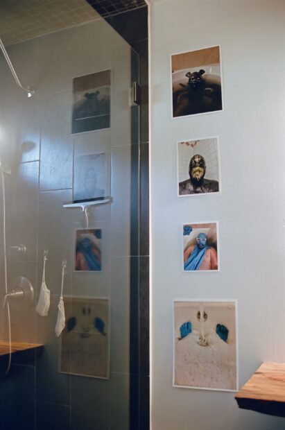 Artworks are hung on a wall next to a shower.