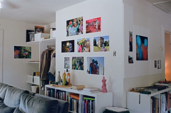 Artworks are hung on a wall above a bookshelf.