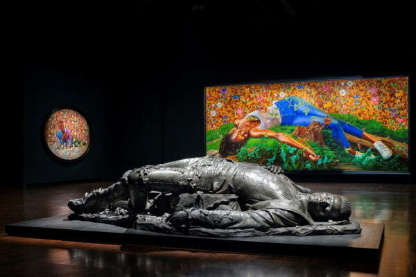 An installation photograph of a sculpture and paintings by Kehinde Wiley featuring young Black people who have been slain.