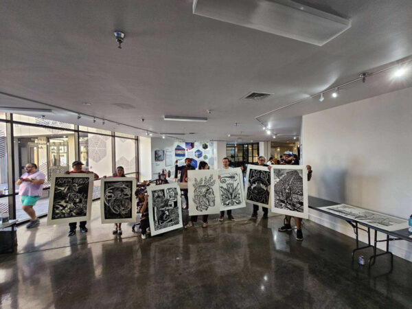 Photo of visitors holding the resulting prints at a live printing pachanga in El Paso