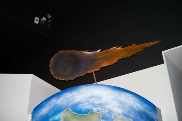 Photo of a maquette of a comet above a display of a planet