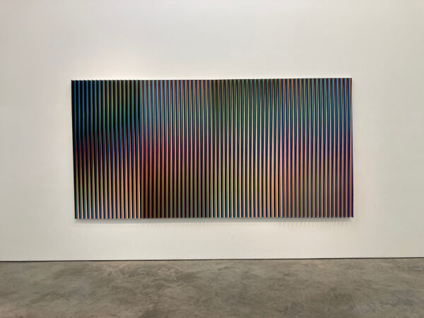 A rectangular artwork consisting of very thin vertical stripes of a range of colors, separated by clear pieces of colored plastic.