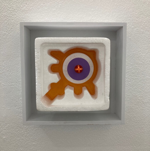A block of styrofoam is filled with orange and purple plastic, within a frame.