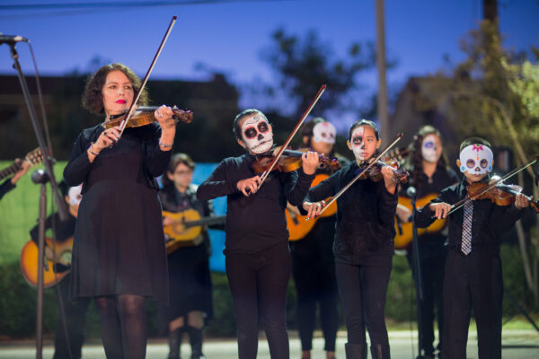A photograph of a handful of violinists dressed for Dia de los Muertos.