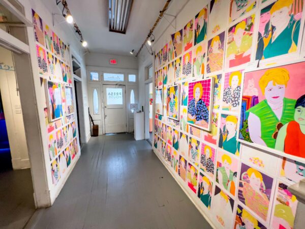 Installation view of technicolor portraits filling a long hallway