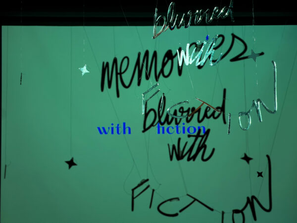 Aluminum words in cursive hanging in front of a green screen