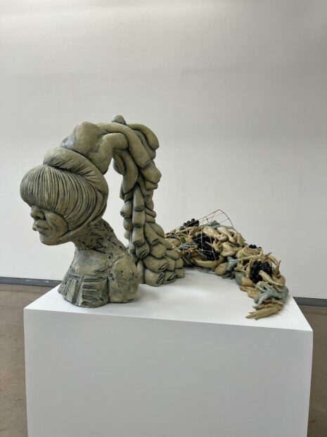 A ceramic sculpture by Misty Gamble featuring the bust of a figure with a cascading hair piece.