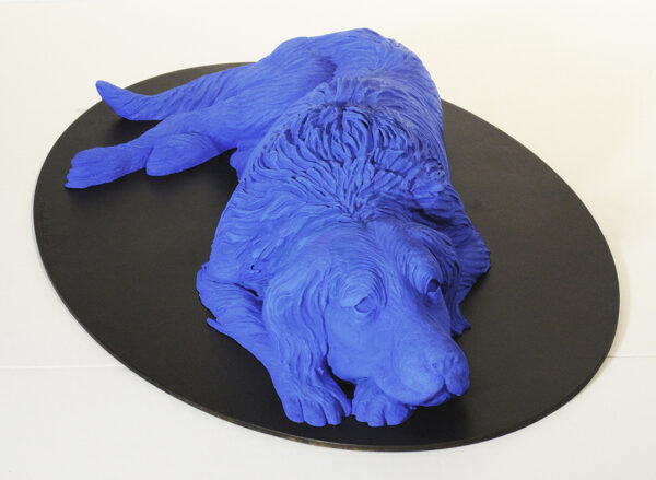 Sculpture of a blue dog lying on a black oval