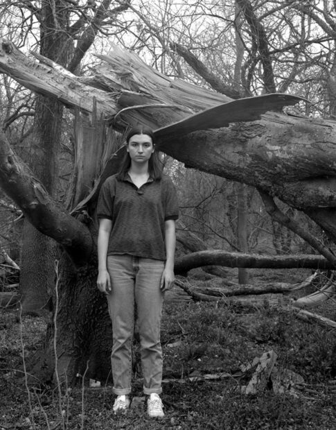 Black and white photo of Ashley Allen in front of a fallen tree