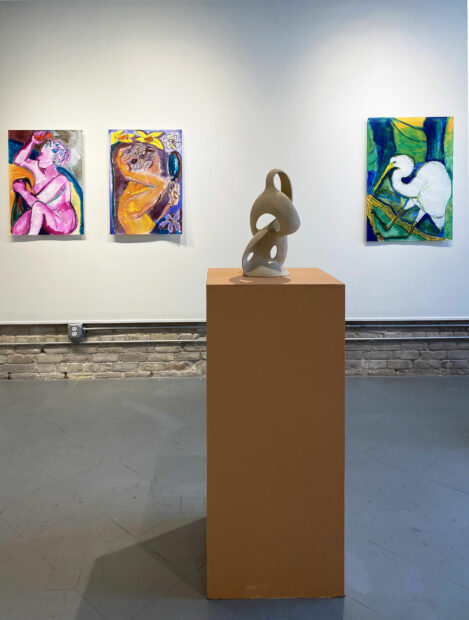 Installation view of three large ink paintings on paper and an organic shaped ceramic vessel on a pedestal