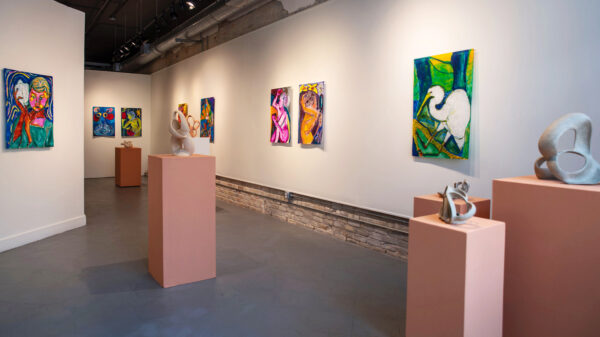 Installation photo of works hanging on a white wall and ceramic sculptures on pedestals