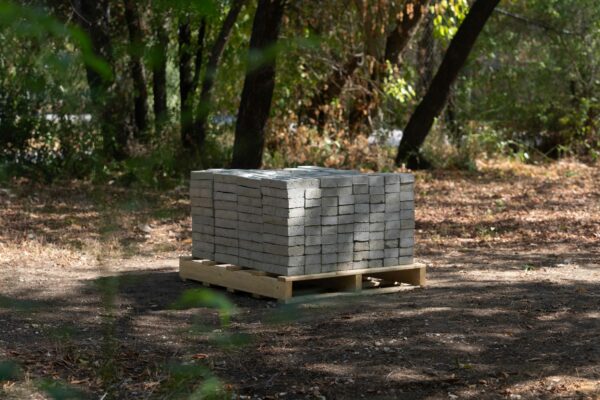 Photo of a stack of concrete bricks stacked on a pallet in a field