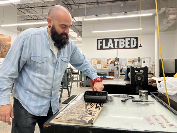 A photograph of Enrique Figueredo inking a print at Flatbed Press.