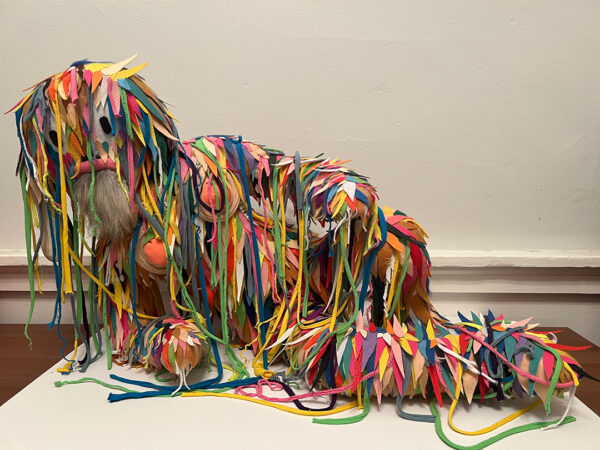 A photograph of a mixed media sculpture by Jason Villegas of a figure covered in strings and fabric.