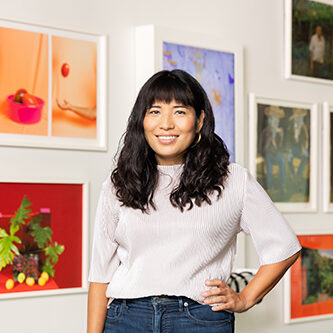 A photograph of artist Lorena Molina in front of her work.