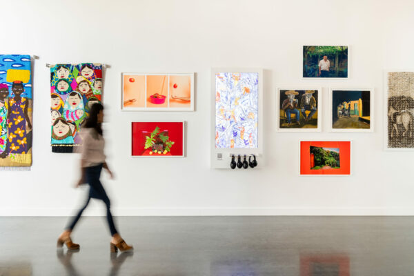 An installation photograph depicting a person walking through a gallery.