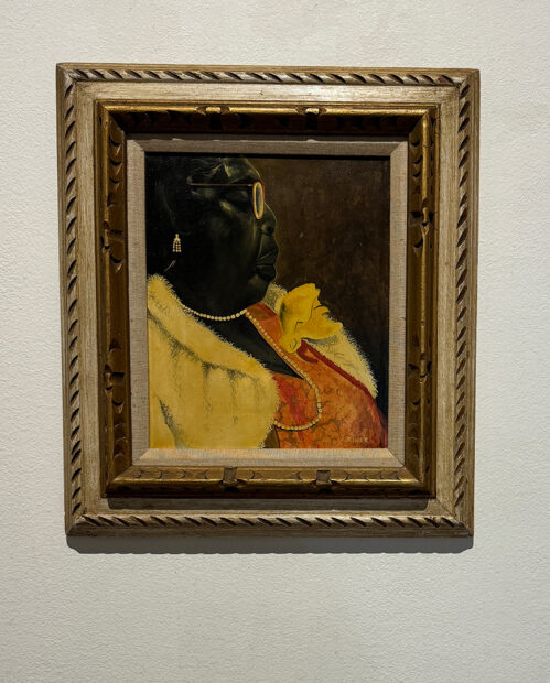 A photograph of a painting by Charles Criner featuring a Black woman wearing an orange dress and a yellow coat.