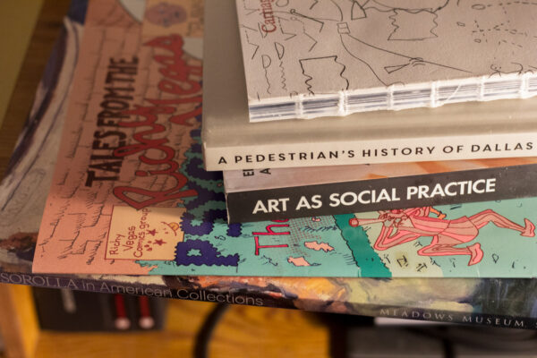 A selection of books stacked on top of each other on the Assistant Editor's desk