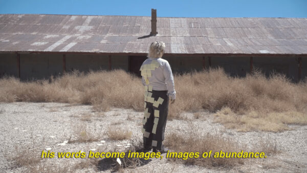 A still image from video work by Hannah Spector featuring a figure facing a large building with text at the bottom of the image that reads, "his words become images, images of abundance."