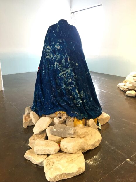 Installation of a large sculpture of a cloak on stones