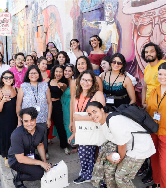 A photograph of a group of people gathered outside of a mural.