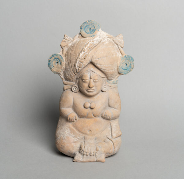 A photograph of a small earthenware sculpture of a seated male figure.
