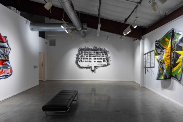 Installation view of paintings on tarp on the left and right walls, and a graphite wall drawing of a billboard armature in the center