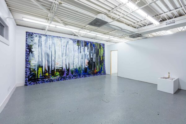 Installation view of a large scale painting on tarp and posters on a white pedestal
