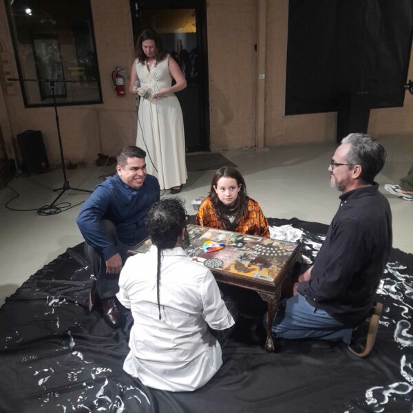 Photo of four people sitting around a small table during an artist performance