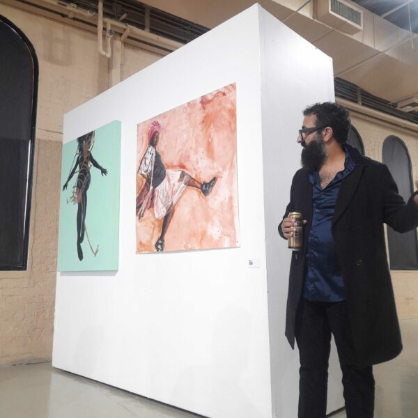 Photo of artist and curator Michael Anthony Garcia in front of two drawings