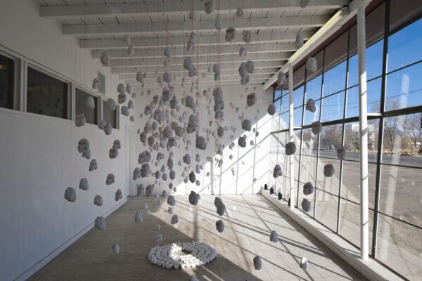 A photograph of an installation of ceramic hearts hanging on wires.