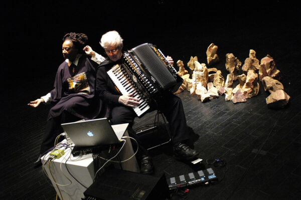 Documentation photo of two people performing, one playing an accordion