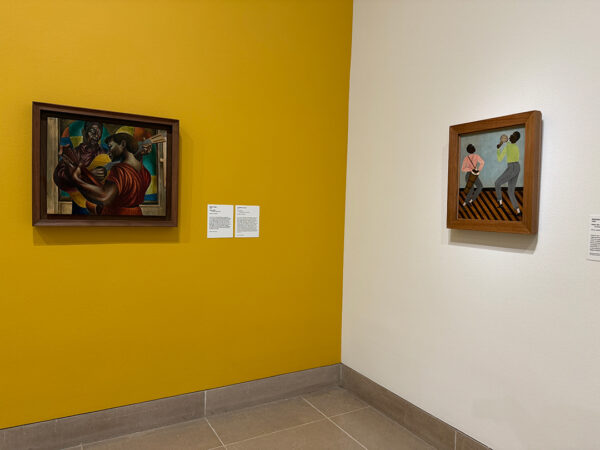 An installation image of paintings by Charles White and Heitor dos Prazeres.