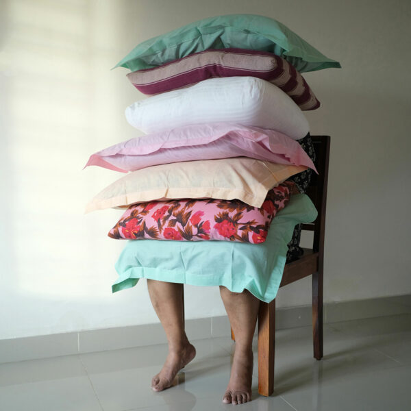 Photo of a performaance of a person sitting in a chair with a stack of pillows on their lap