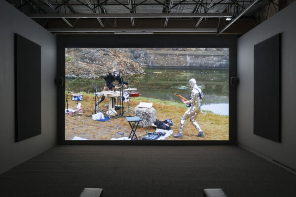 Video installation of people playing instruments outdoors in the landscape